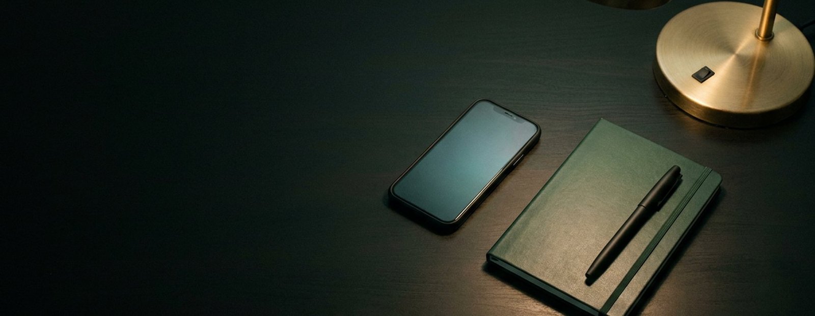 Mesa escura com o celular e o caderno prontos para a conversa começar