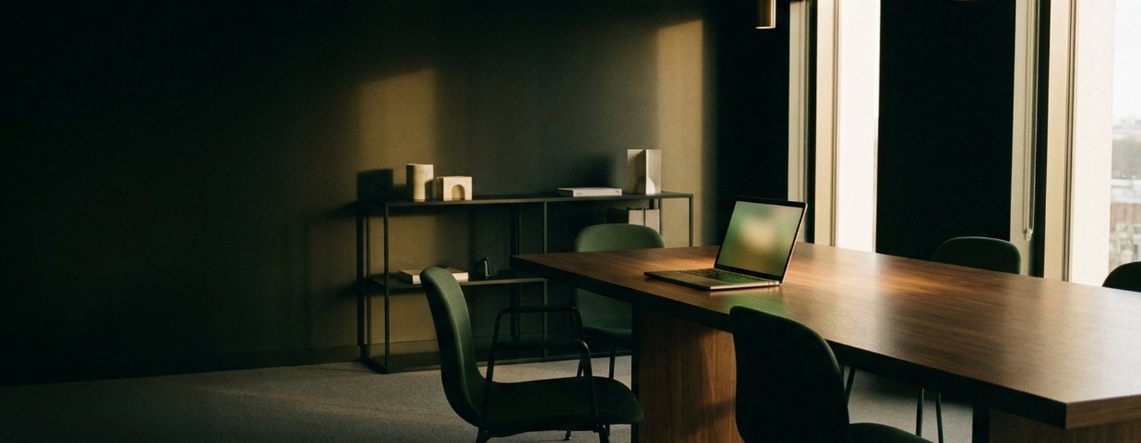 Sala de reunião do escritório no fim do dia, com o notebook aberto sobre a mesa